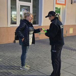 Na zdjęciu policjanci rozdają przechodniom odblaski.