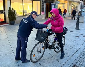 Na zdjęciu policjanci rozdają przechodniom odblaski.