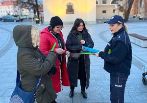 Na zdjęciu policjanci rozdają przechodniom odblaski.