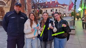 Na zdjęciu policjanci rozdają przechodniom odblaski.