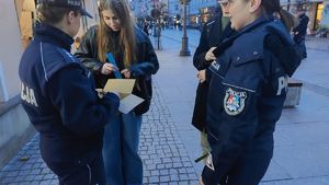 Na zdjęciu policjanci rozdają przechodniom odblaski.