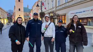 Na zdjęciu policjanci rozdają przechodniom odblaski.