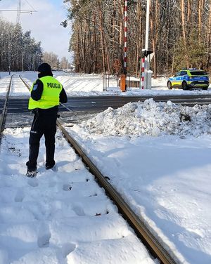 Na zdjęciu umundurowany policjant w żółtej kamizelce odblaskowej z napisem policja na plecach.