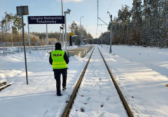Na zdjęciu umundurowany policjant w żółtej kamizelce odblaskowej z napisem policja na plecach.