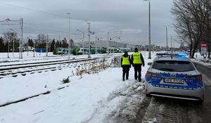 Na zdjęciu umundurowany policjant w żółtej kamizelce odblaskowej z napisem policja na plecach.
