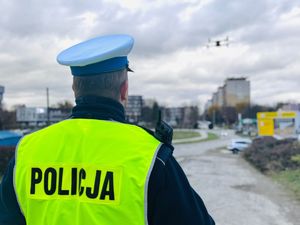 Na zdjęciu umundurowany policjant ruchu drogowego obsługuje drona.