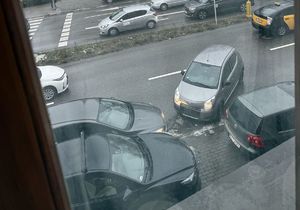 Na zdjęciu pojazdy stojące na poboczu i ruch uliczny.