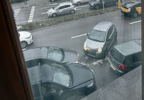 Na zdjęciu pojazdy stojące na poboczu i ruch uliczny.