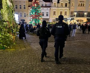 Na zdjęciu umundurowani policjanci, w tle Miasteczko Bożonarodzeniowe.