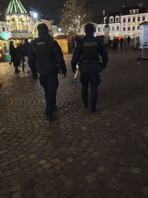 Na zdjęciu umundurowani policjanci, w tle Miasteczko Bożonarodzeniowe.