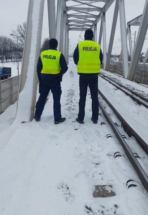 Na zdjęciu dwóch umundurowanych policjantów na terenach kolei.