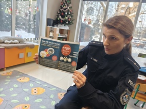 Na zdjęciu policjantka z kartką zawierającą ostrzeżenia.