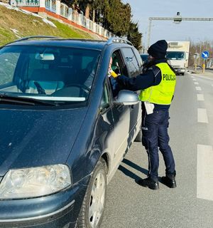 Na zdjęciu umundurowana policjantka ruchu drogowego podczas kontroli stanu trzeźwości kierującego pojazdem.