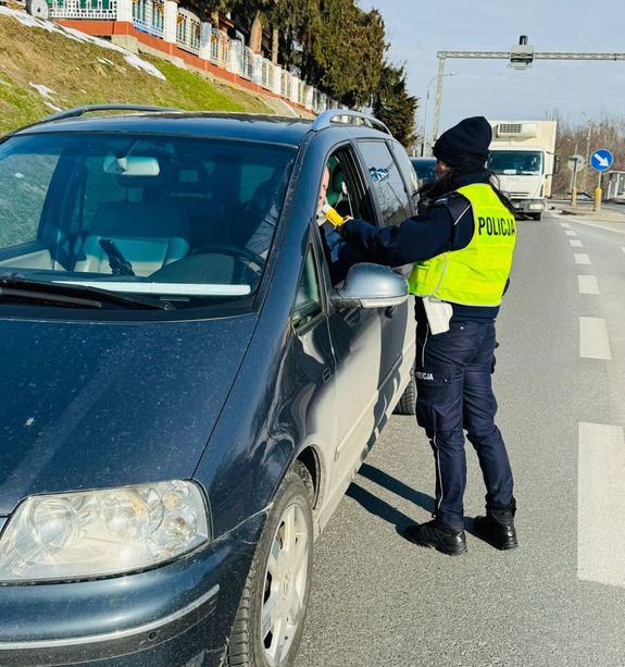 Na zdjęciu umundurowana policjantka ruchu drogowego podczas kontroli stanu trzeźwości kierującego pojazdem.