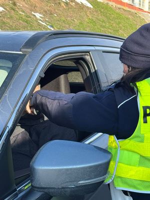 Na zdjęciu umundurowana policjantka ruchu drogowego podczas kontroli stanu trzeźwości kierującego pojazdem.