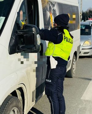 Na zdjęciu umundurowana policjantka ruchu drogowego podczas kontroli stanu trzeźwości kierującego pojazdem.