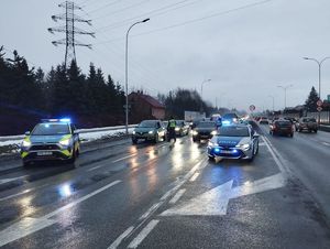 Na zdjęciu radiowozy z włączonymi sygnałami świetlnymi i inne pojazdy.