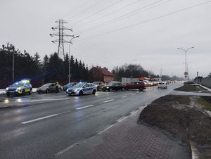 Na zdjęciu radiowozy z włączonymi sygnałami świetlnymi i inne pojazdy.