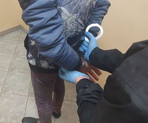 Na zdjęciu stojący tyłem mężczyzna, na ręce trzymane z tyłu na zakładane kajdanki.