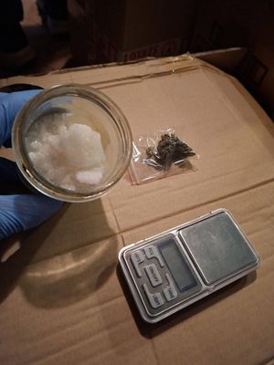 Na zdjęciu słoiczek z białymi kryształkami, obok waga.