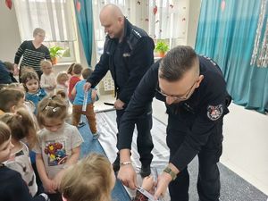 Na zdjęciu dzielnicowi rozdający odblaski dzieciom.