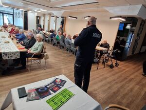 Na zdjęciu policjant oraz uczestnicy spotkania.