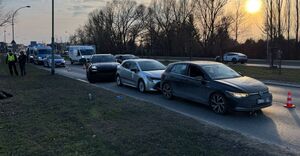Na zdjeciu trzy pojazdy, jakie brały udział w zdarzeniu drogowym, jeden stoi za drugi, za nimi policyjne radiowozu. W tle ruch uliczny.