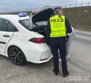 Na zdjęciu policjantka kontrolująca taksówkę.