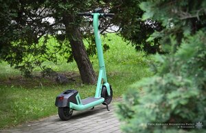 Zielona hulajnoga zaparkowana na chodniku