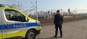Na zdjeciu umundurowany policjant obok policyjny radiowóz.