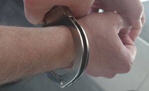 Na zdjeciu dłonie, na których założone są kajdanki.