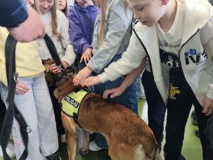 Na zdjęciu dzieci głaszczące psa policyjnego.