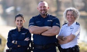Na zdjęciu troje umundurowanych policjantów, dwie kobiety, pośrodku nich uśmiechnięty mężczyzna.