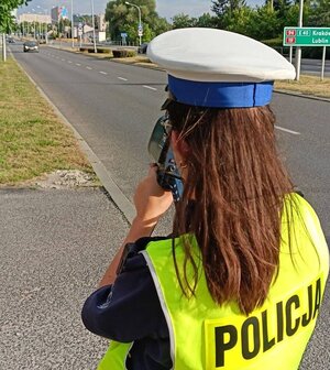 Na zdjęciu policjantka ruchu drogowego mierzy prędkość jadącym samochodom.
