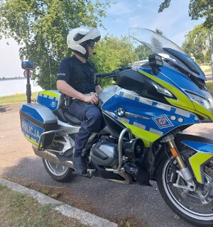 Na zdjeciu umundurowany policjant siedzi na służbowym motocyklu.