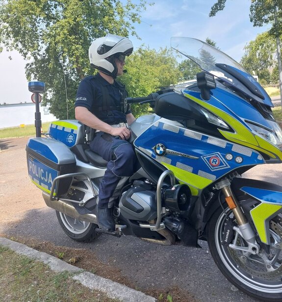 Na zdjeciu umundurowany policjant siedzi na służbowym motocyklu.