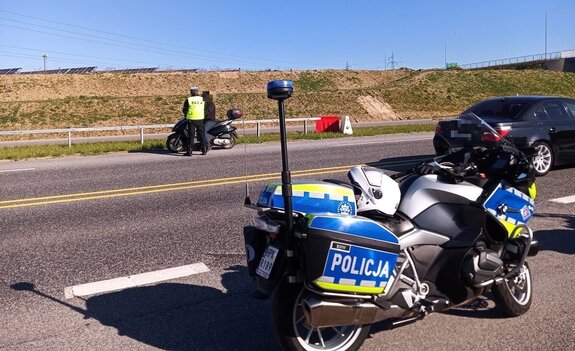 Na zdjęciu umundurowany policjant dokonujący kontroli motocyklisty.