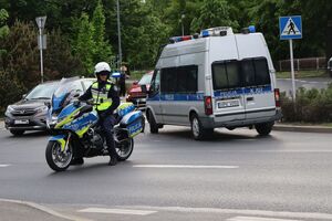 Na zdjęciu policyjny radiowóz i policjant na służbowym motocyklu.