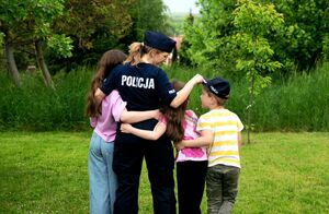 Na zdjeciu umundurowana policjantka z obejmującymi ją dziećmi.