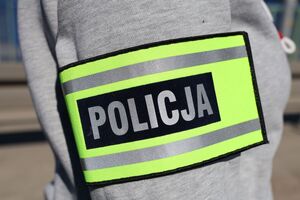 Na zdjeciu naramienna opaska odblaskowa z napisem policja.